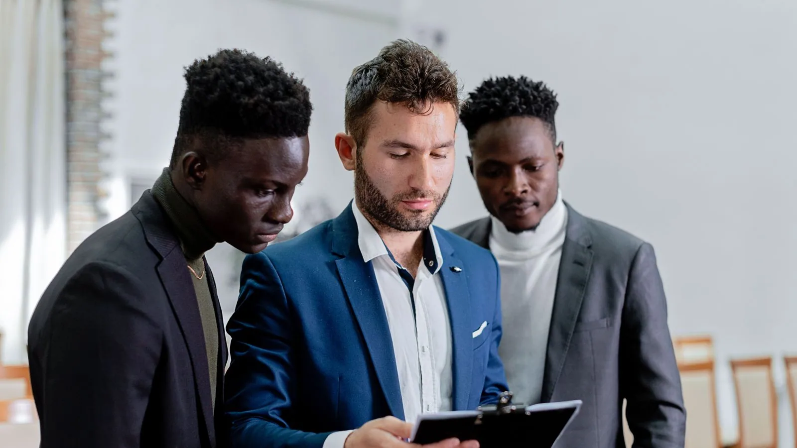 Three colleagues reviewing information on a tablet