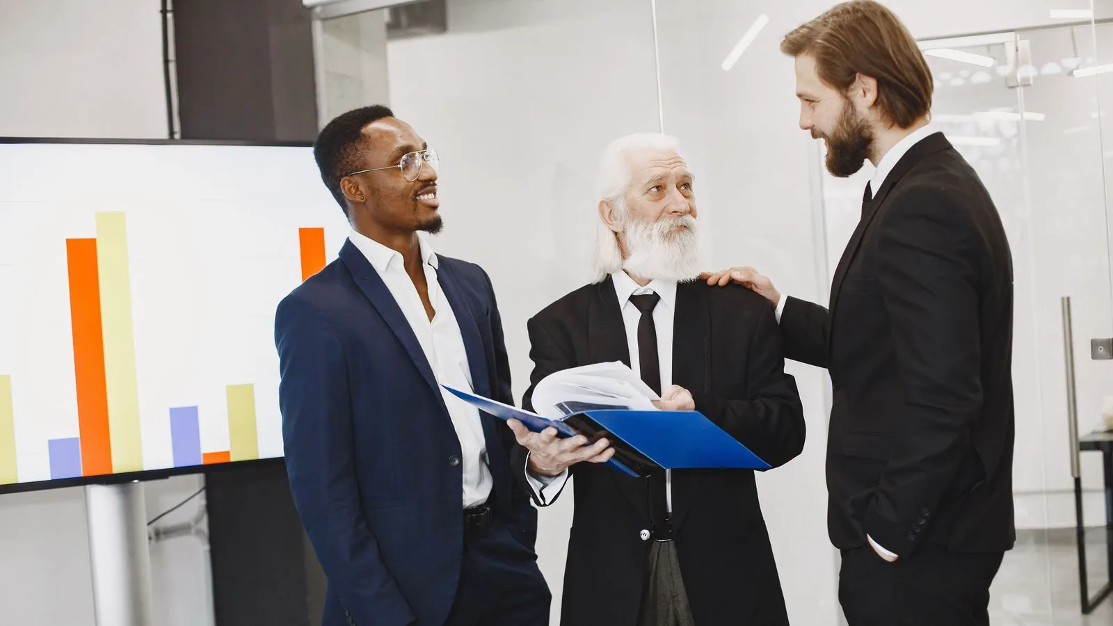 Three businesspeople comparing documents beside a chart