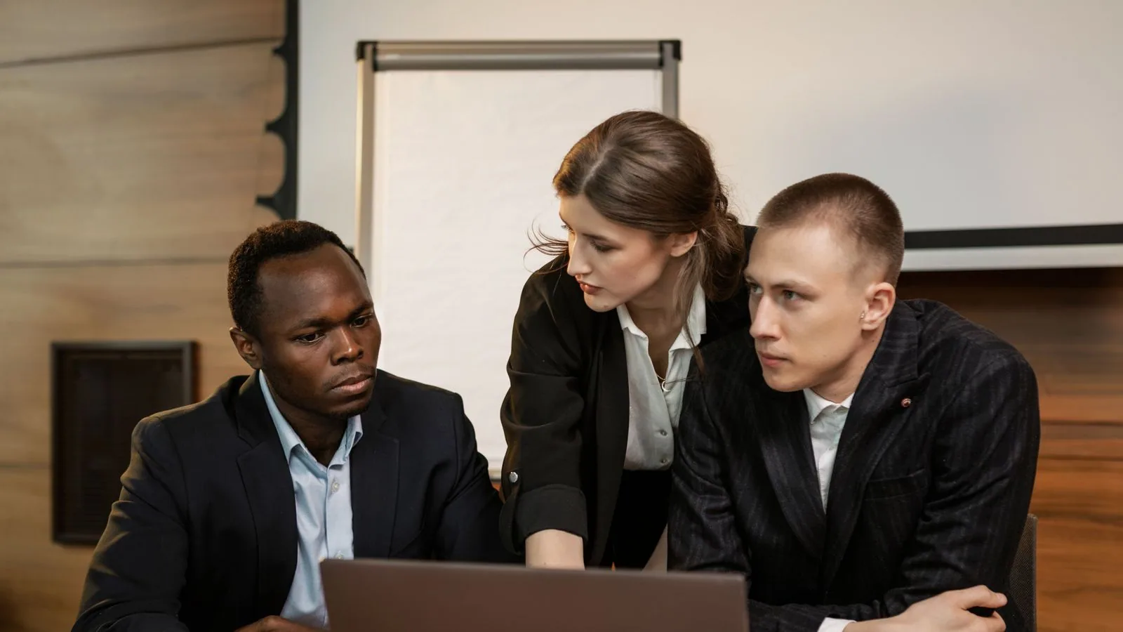 Three colleagues examining information on a laptop