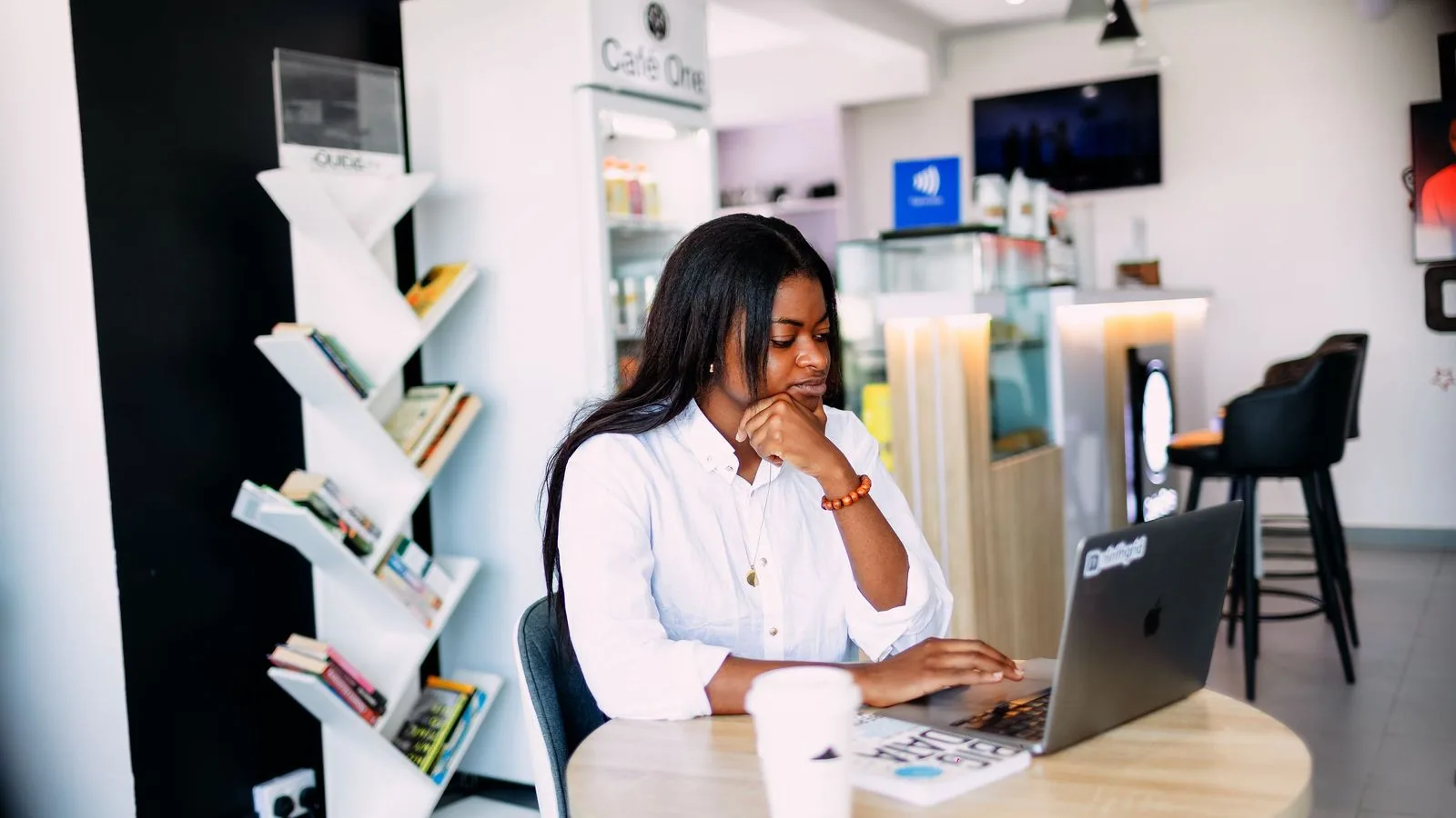 A woman working at a laptop in a cafe