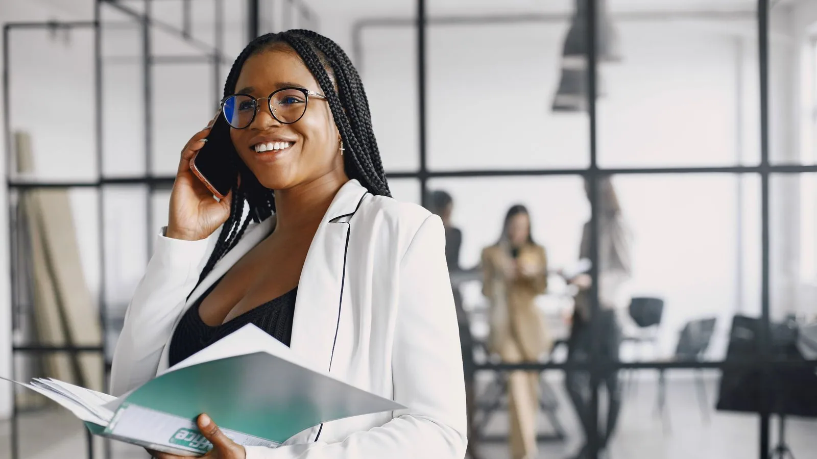A woman taking a phone call while carrying document folders