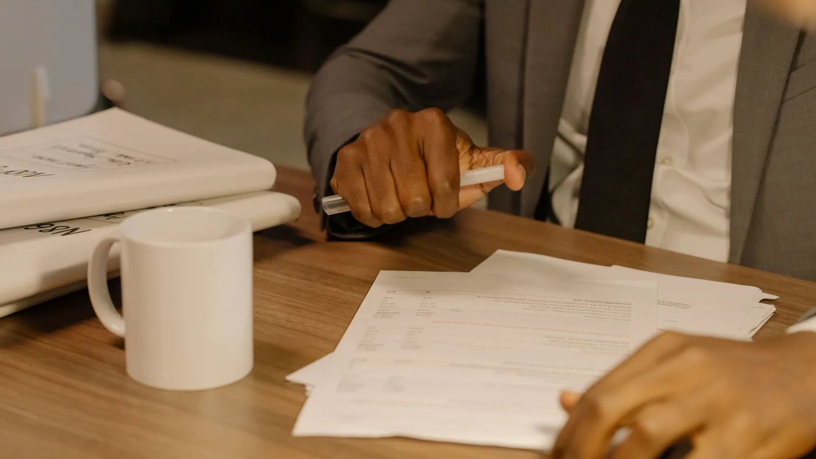 A person reviewing printed paperwork with a pen