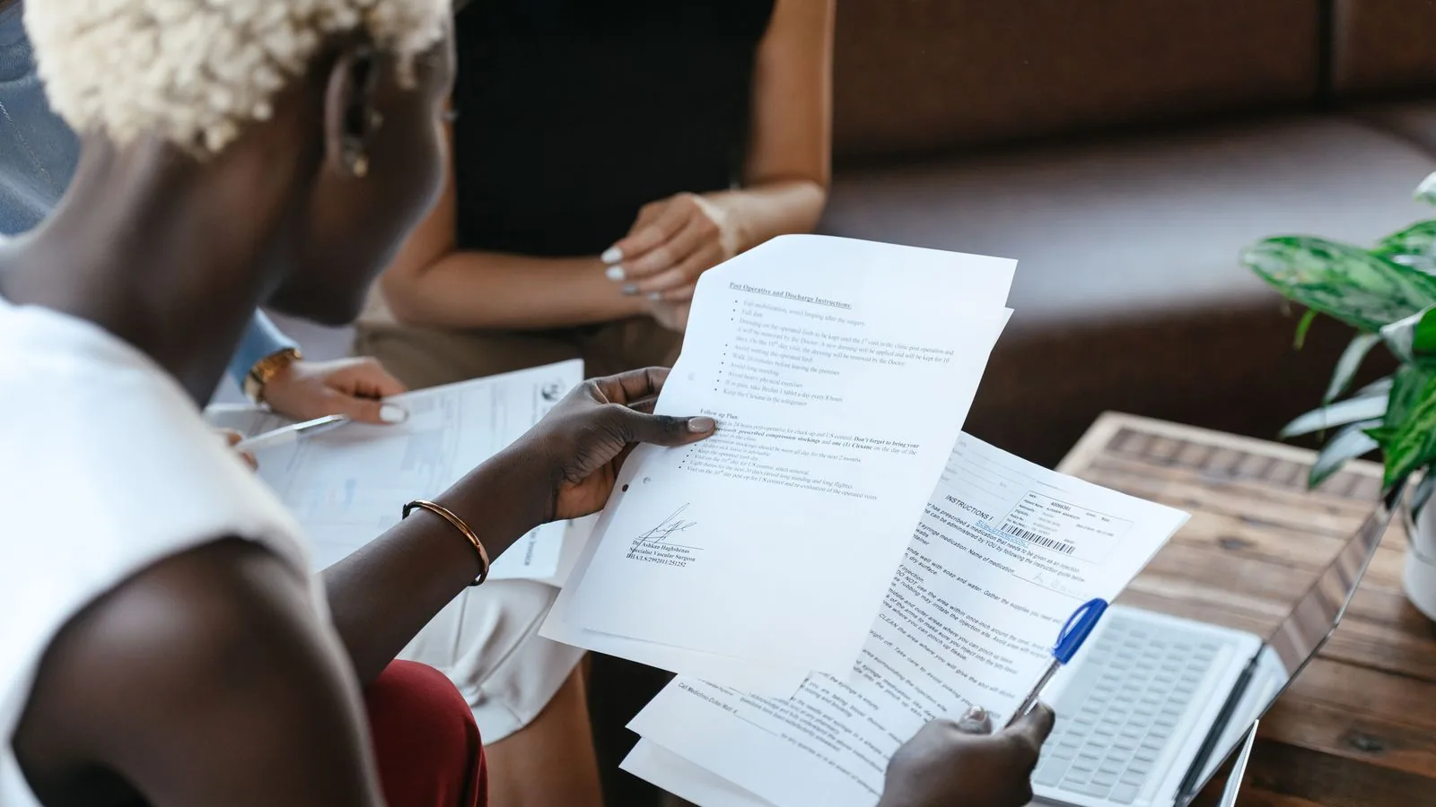 People comparing printed documents beside a laptop