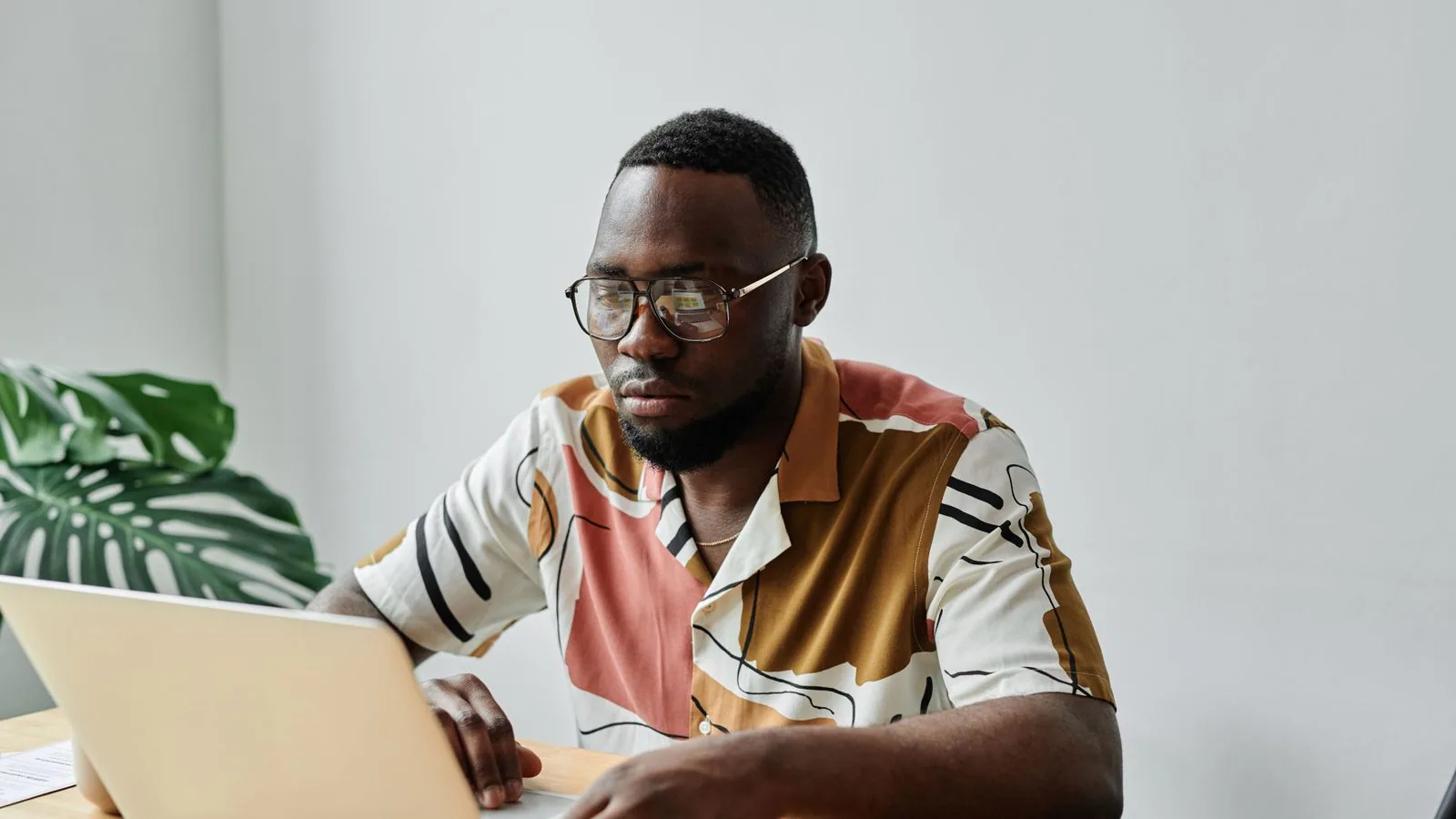 A man wearing glasses working at a laptop