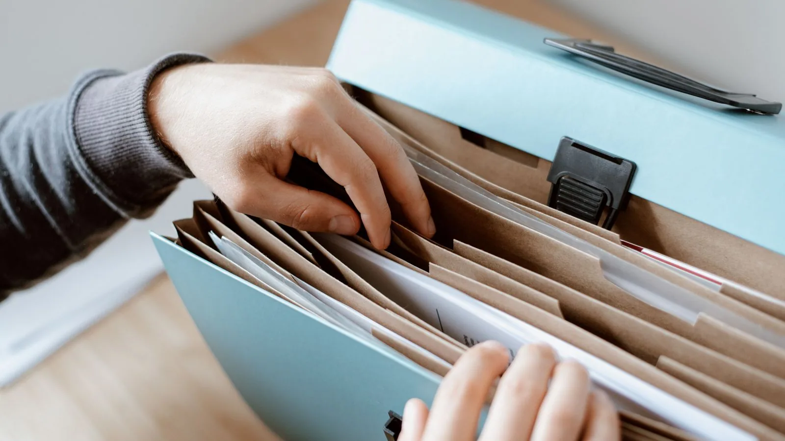 A hand sorting papers in an expanding document file