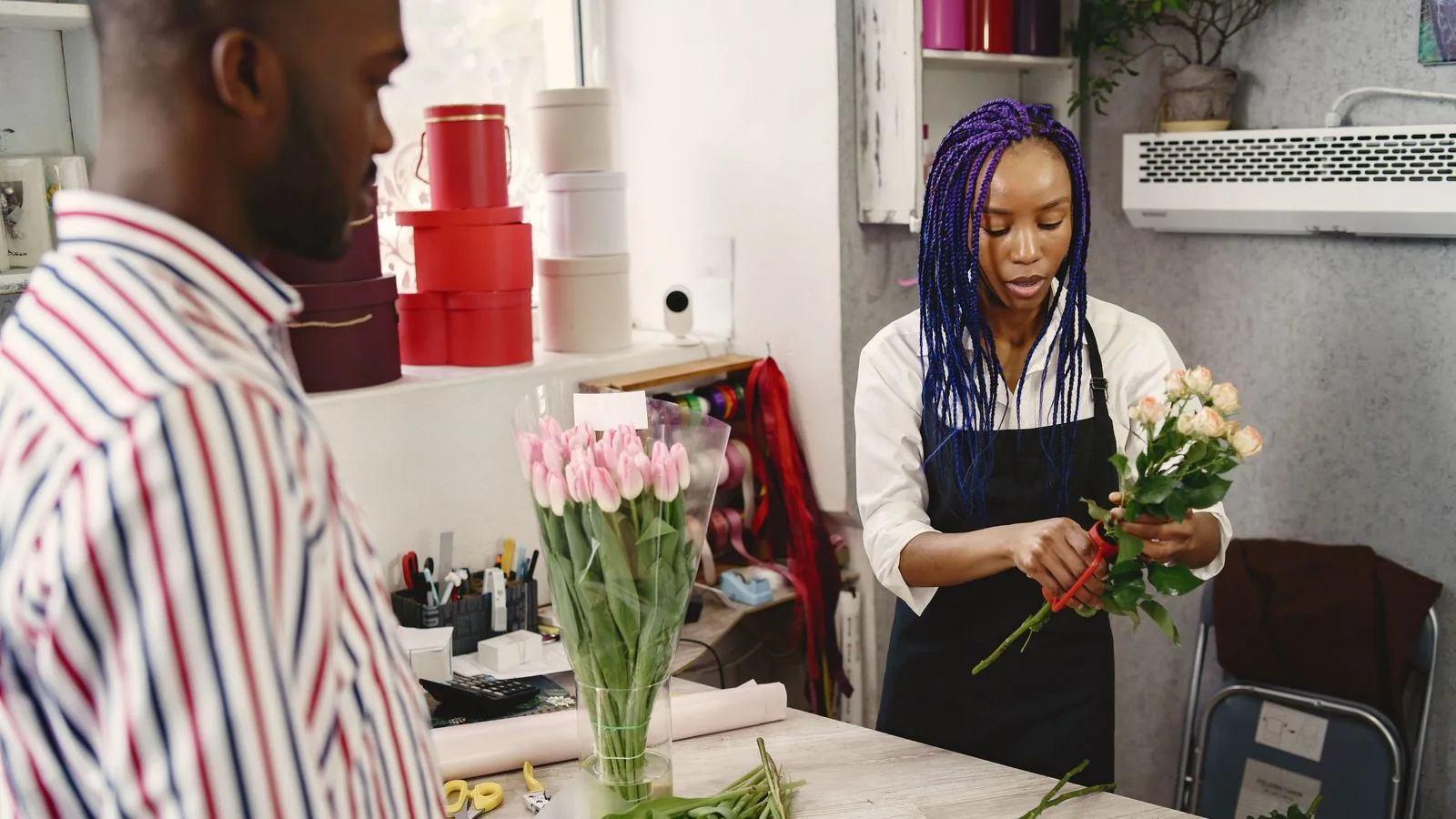 A florist arranging flowers while speaking to a customer