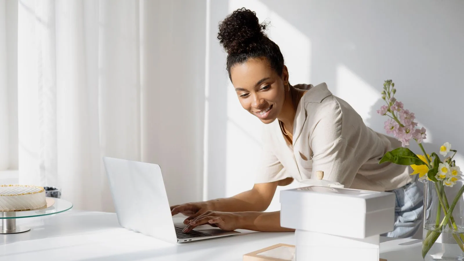 A woman working at a laptop beside stacked packaging boxes