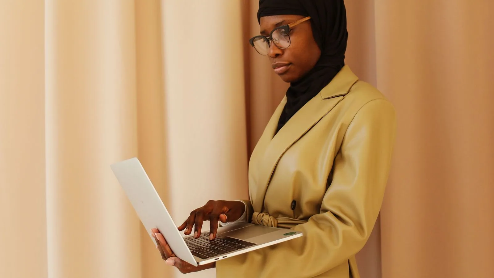 A woman working on a laptop beside a window