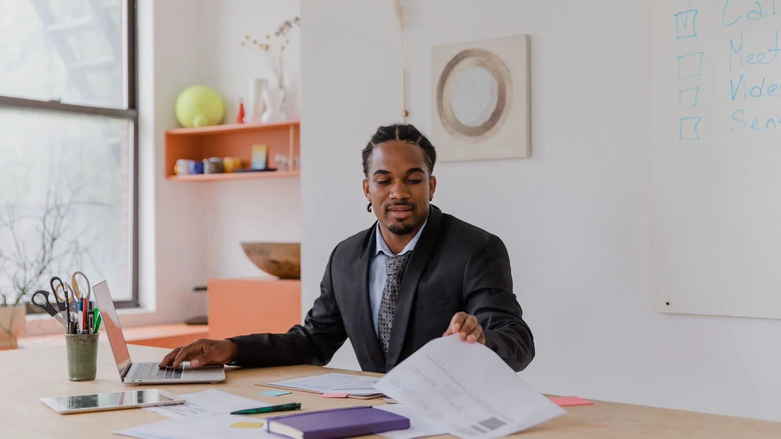 A man comparing paperwork with information on a laptop