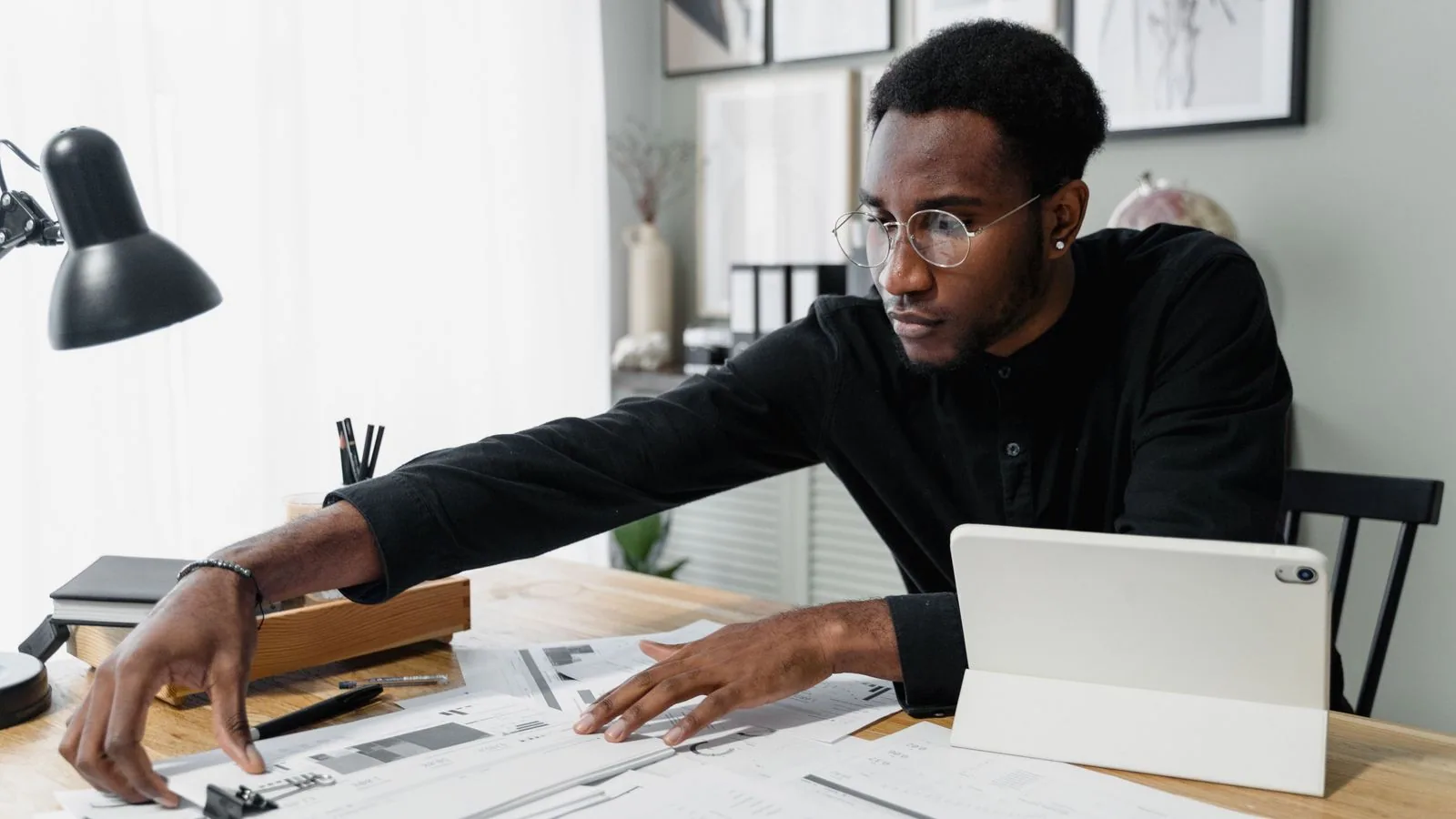 A man organising financial papers beside a tablet
