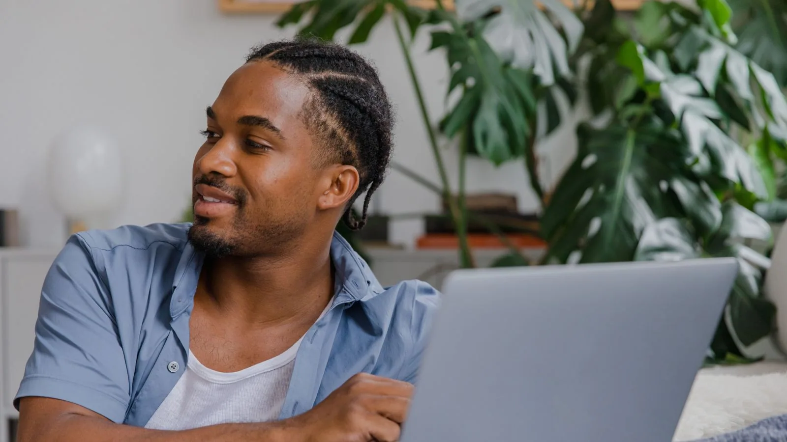 A man using a laptop beside indoor plants