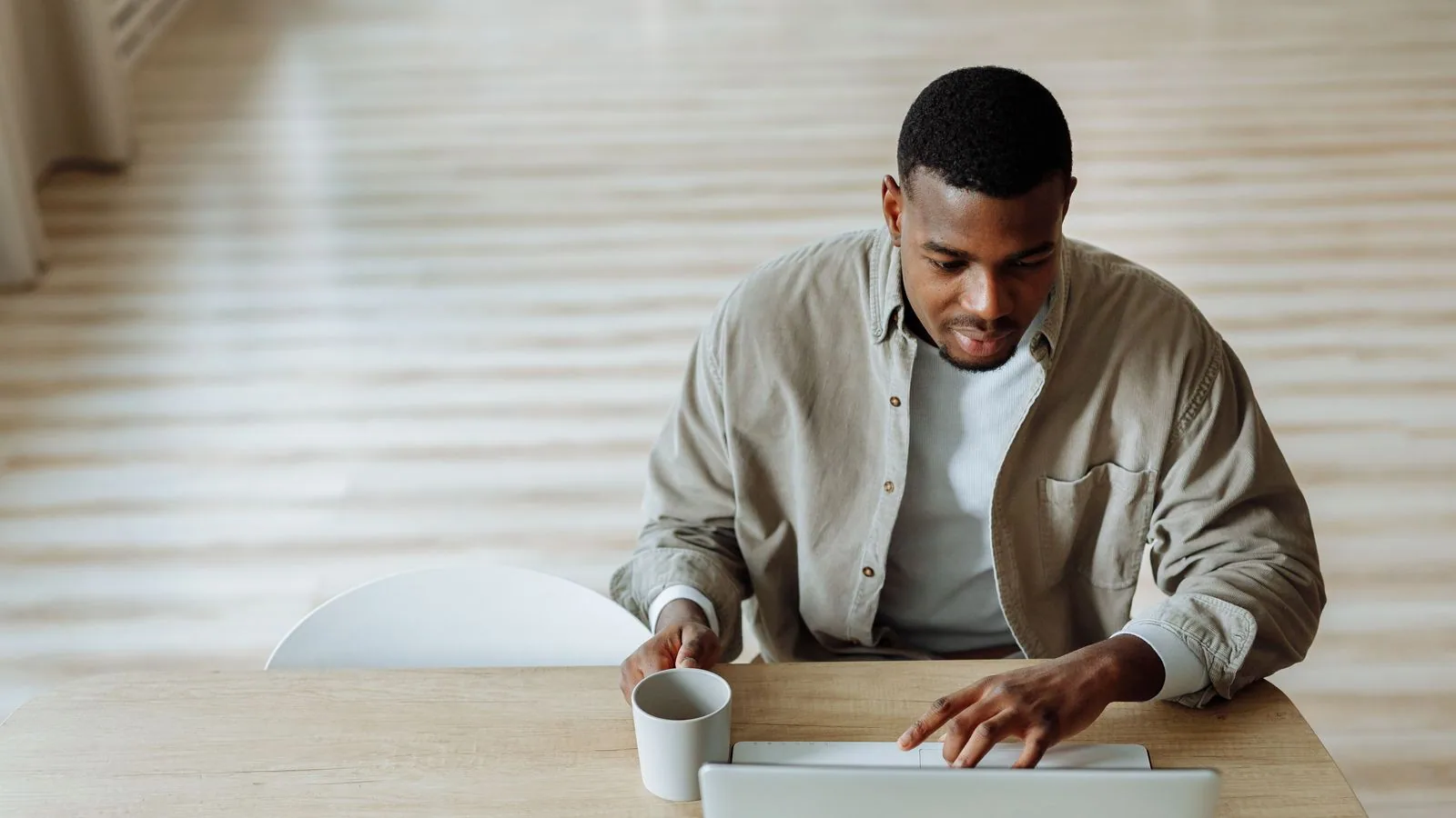 A man using a laptop beside a cup of coffee
