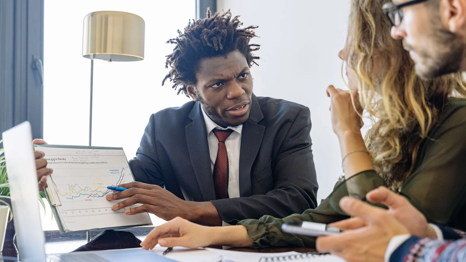 Three people discussing financial documents at a meeting