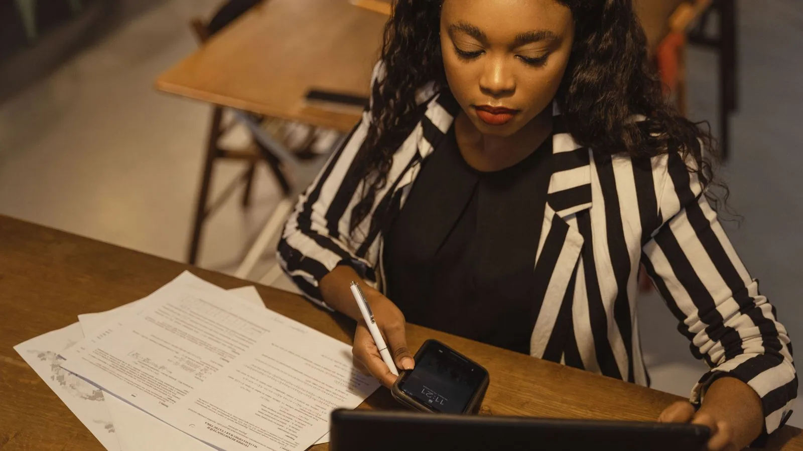 A woman reading paperwork beside an open laptop