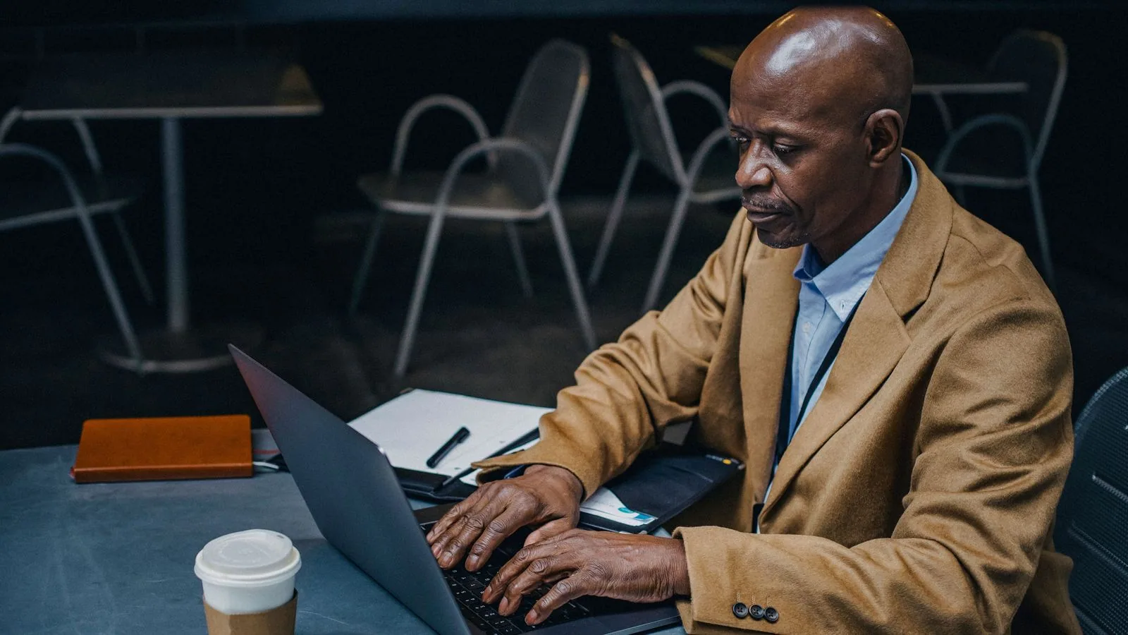 A man reviewing a laptop and notebook at a table
