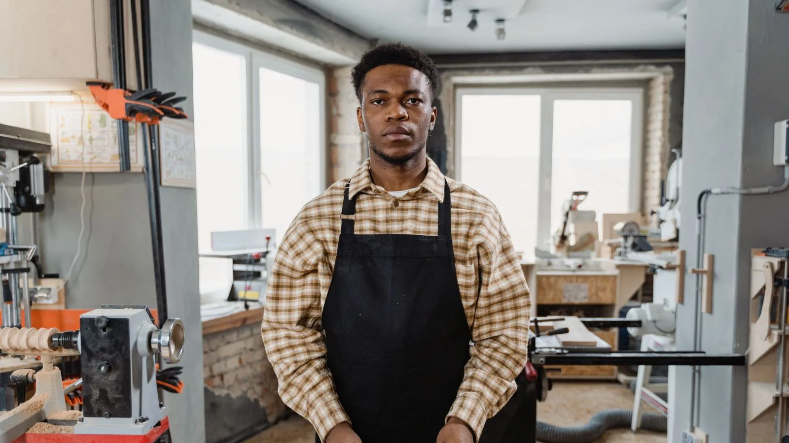 A craftsperson standing at a workshop bench with tools