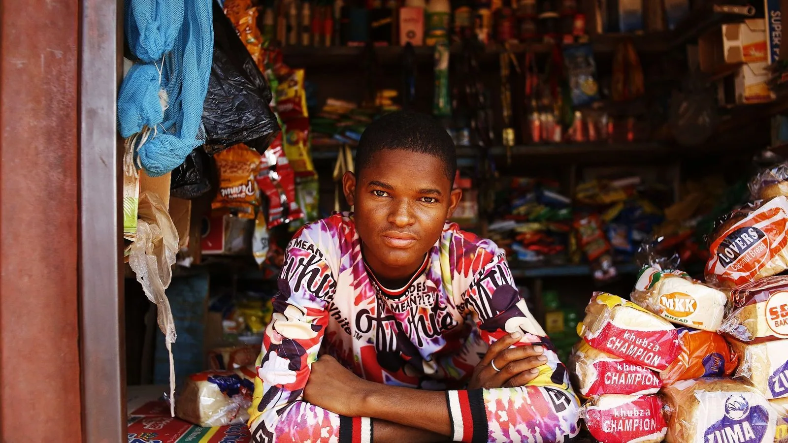A shopkeeper behind a counter of packaged goods