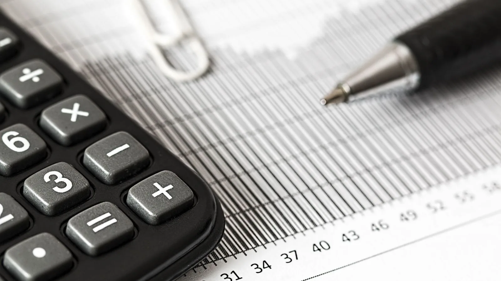A calculator and pen beside printed graphs