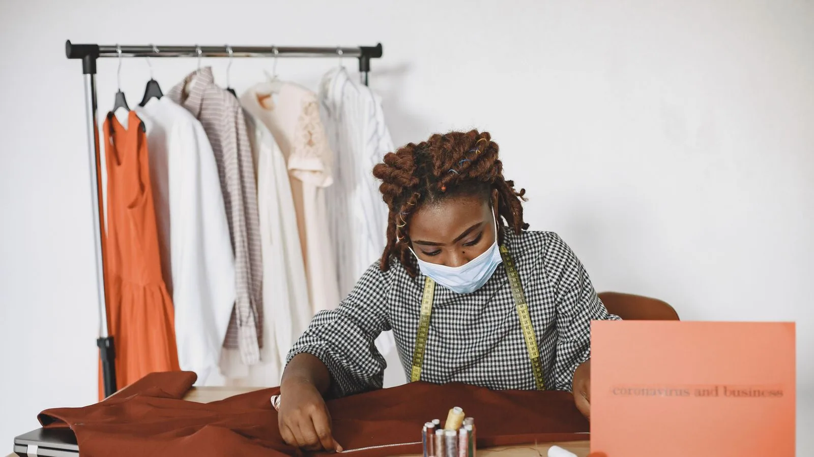A woman working with fabric beside a laptop and sewing equipment