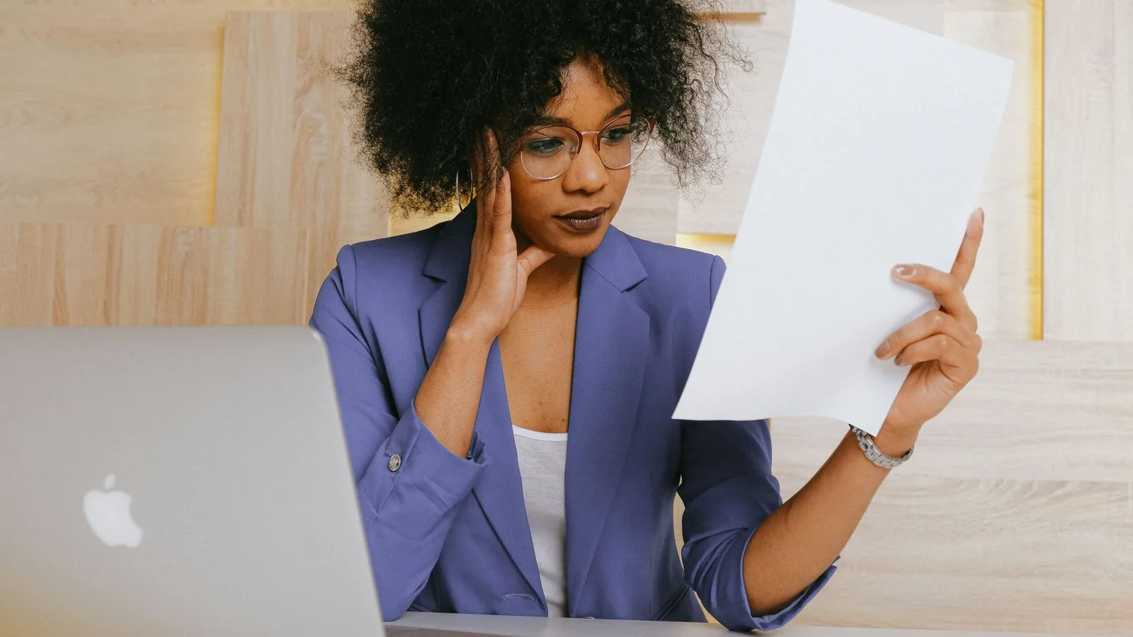 A woman comparing a paper document with her laptop