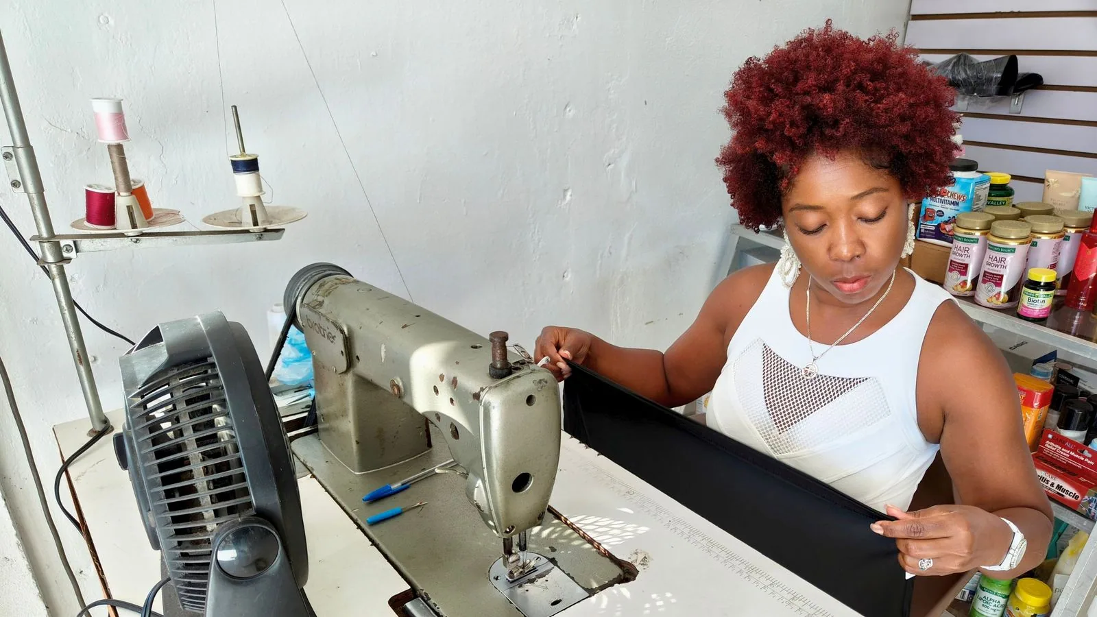 A tailor checking fabric beside a sewing machine