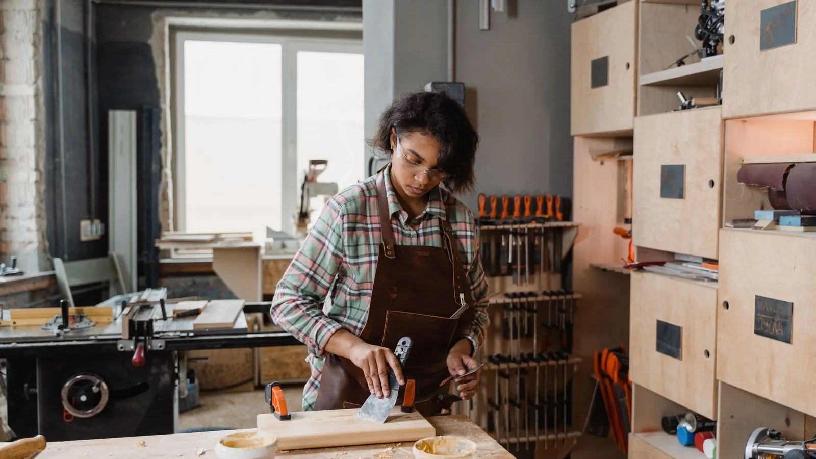 A craftsperson measuring wood in a workshop