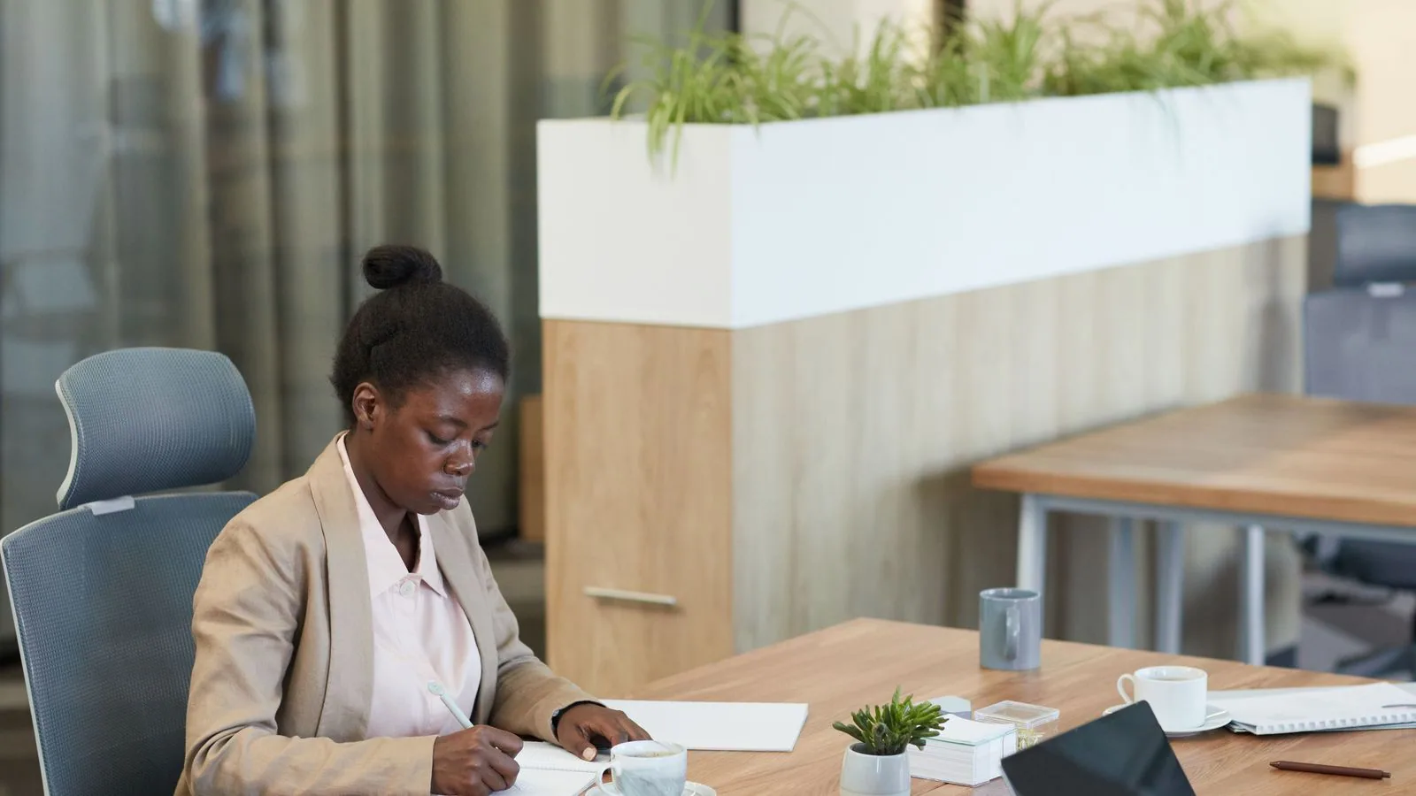 A woman writing notes at an office table