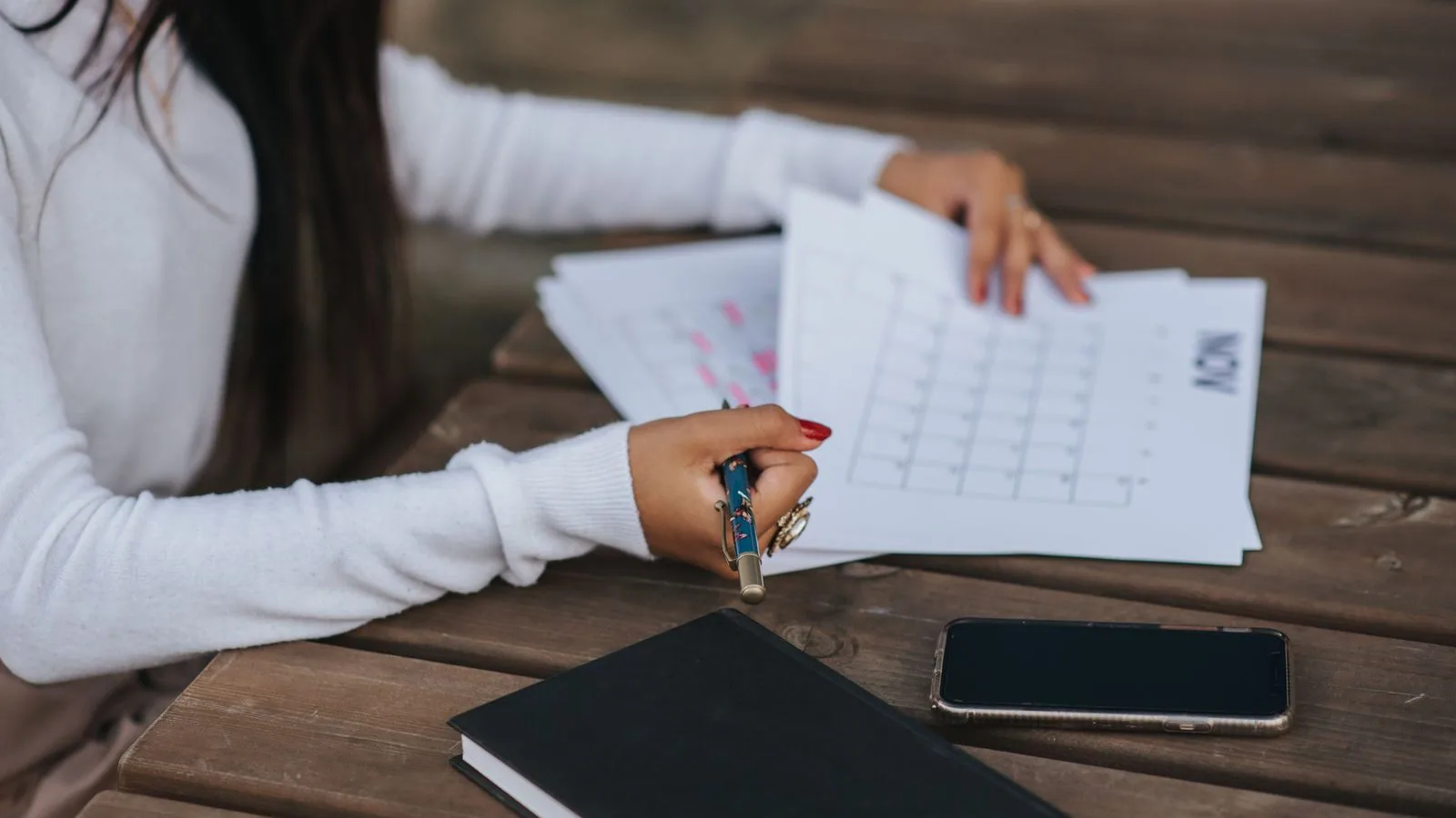 A woman marking a calendar with papers beside her