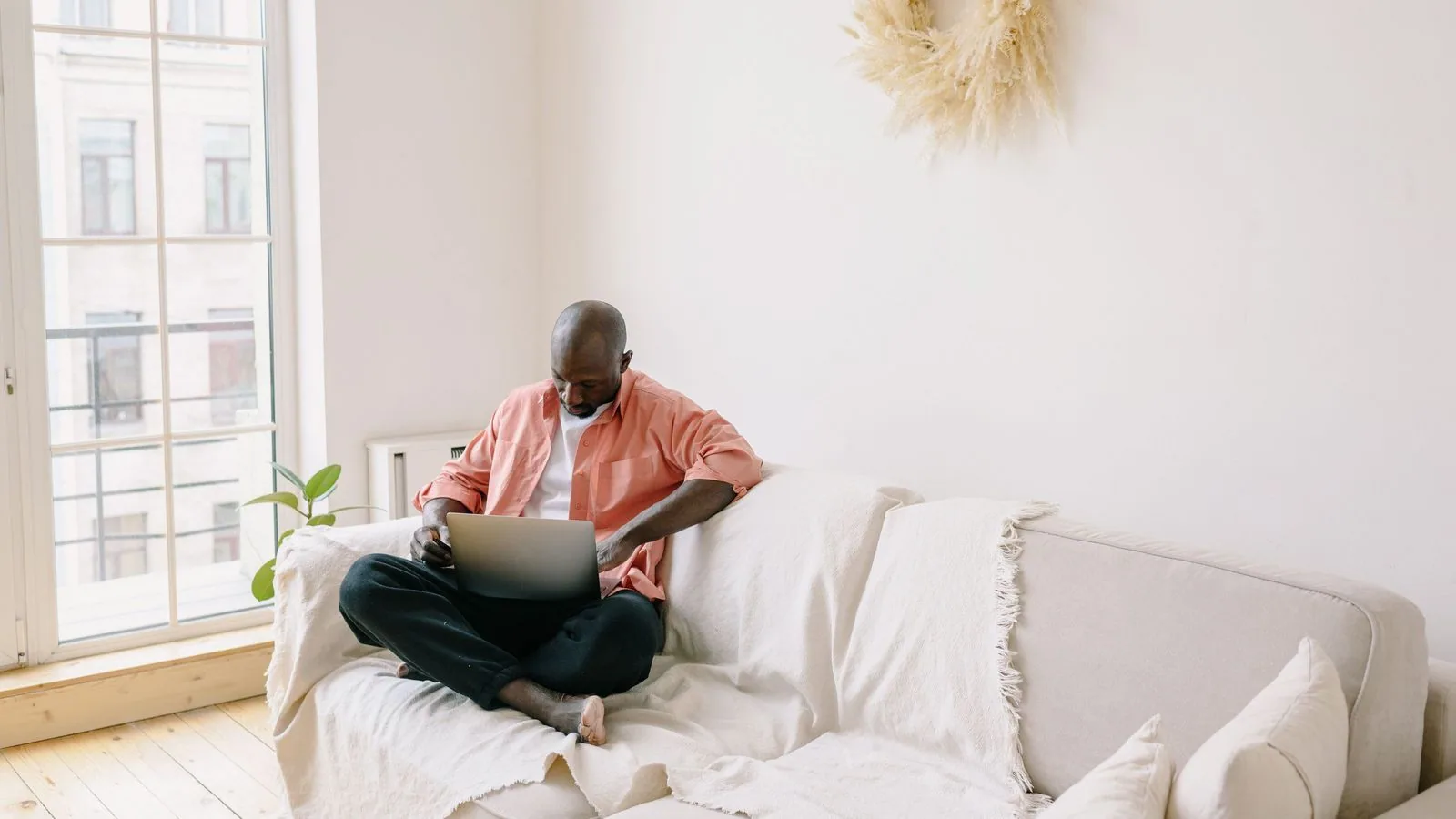 A person working on a laptop while seated on a sofa