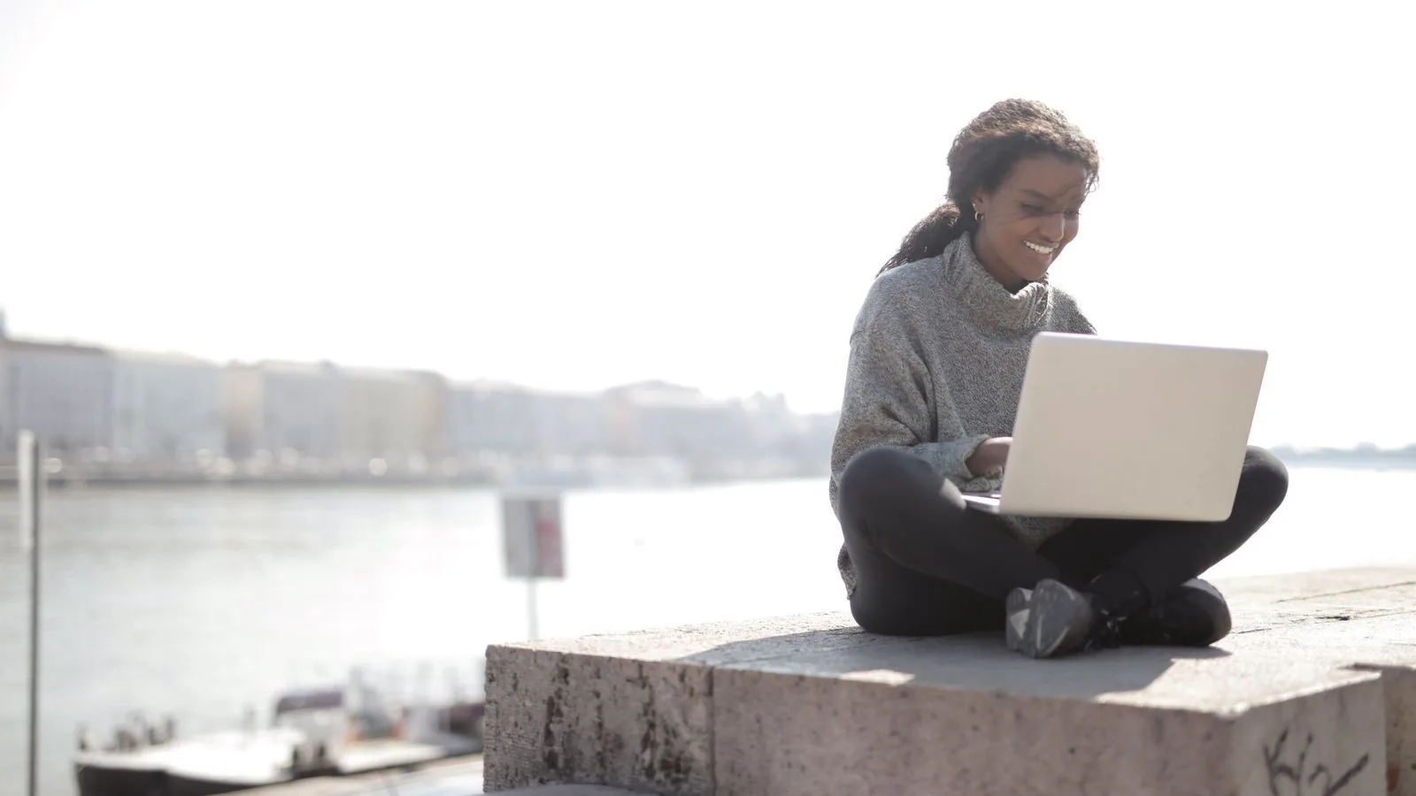 A woman using a laptop while seated outdoors