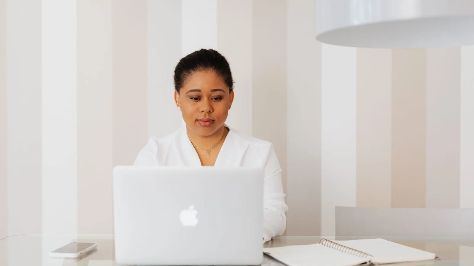 A woman working at a laptop at a white desk