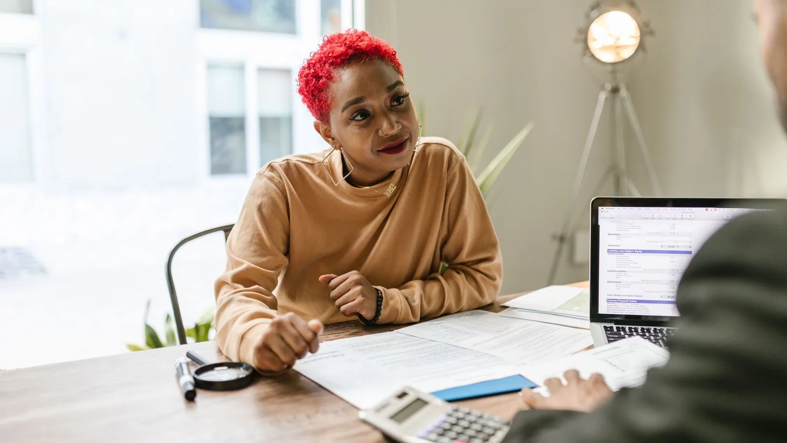 A businesswoman discussing papers across an office desk