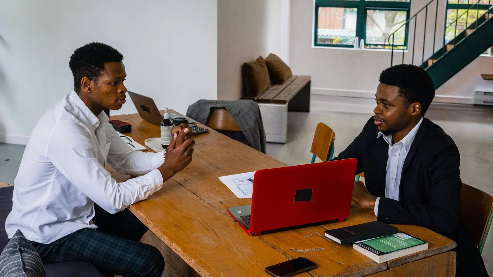 Two businesspeople discussing work over a laptop and notebook