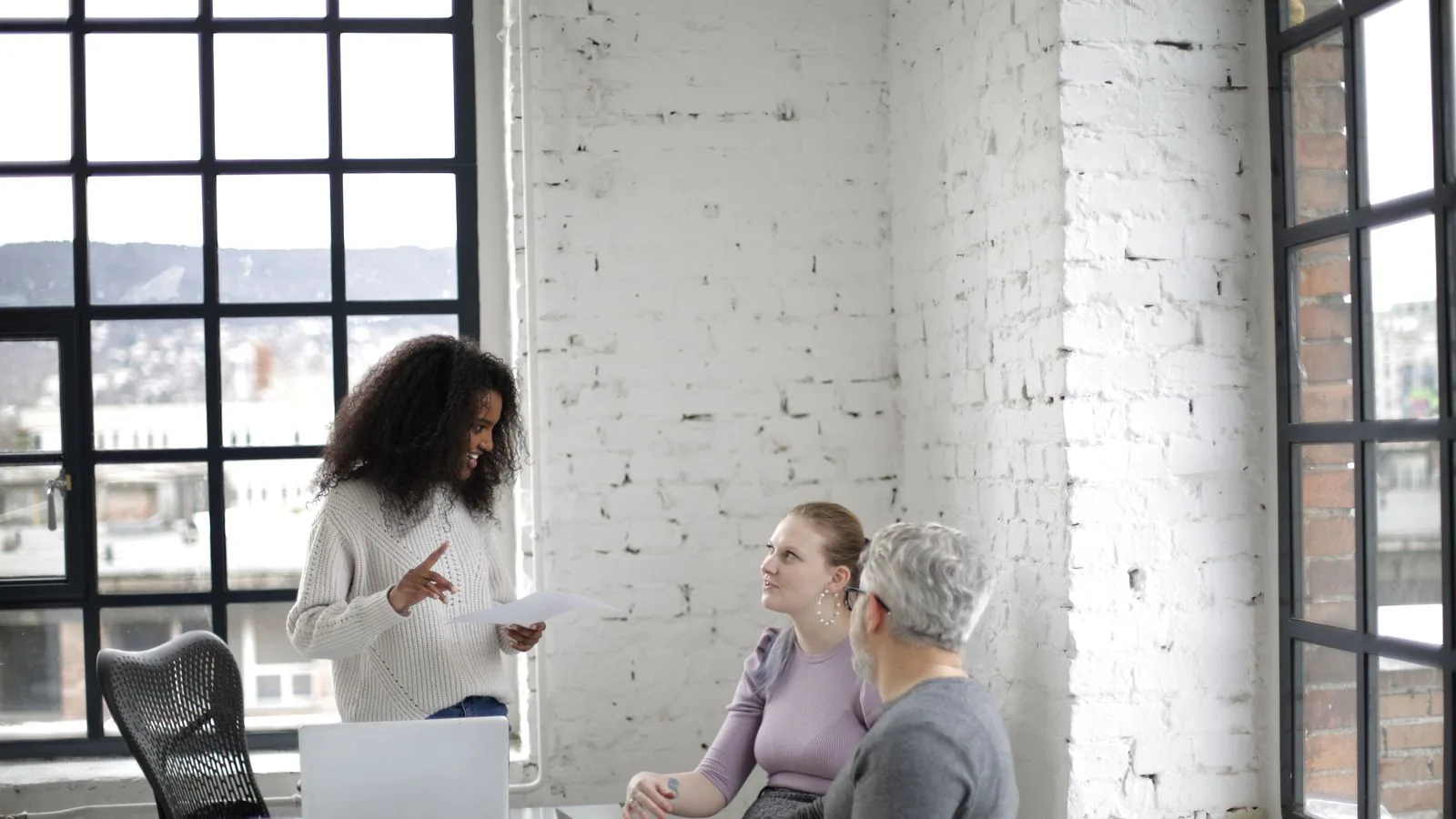 A woman presenting to colleagues in a bright workspace
