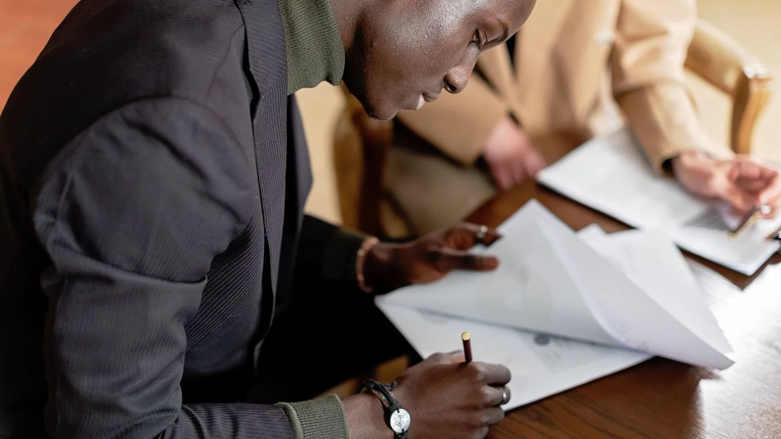 A man signing paperwork during a business discussion