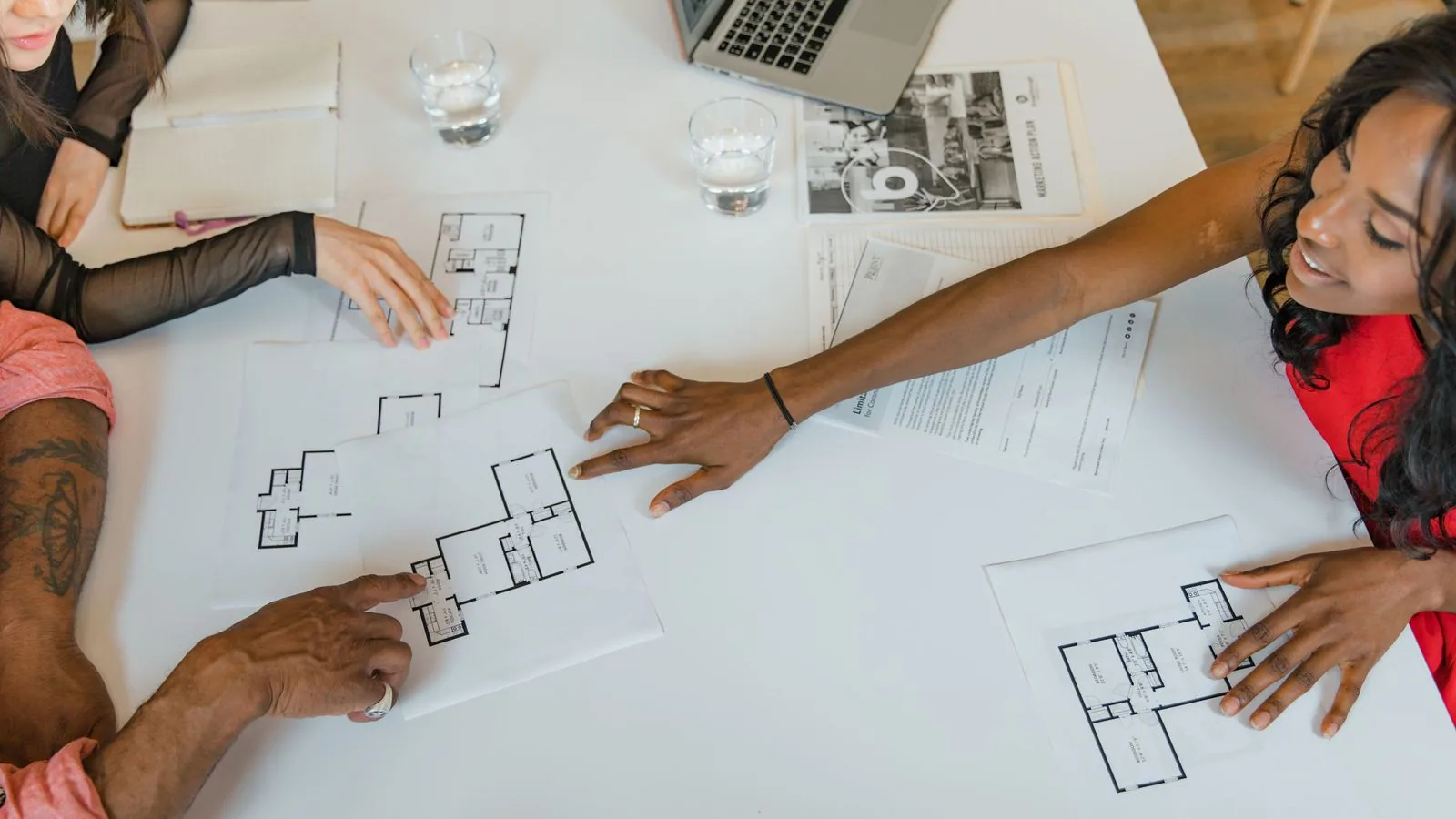 Colleagues comparing printed diagrams around a meeting table