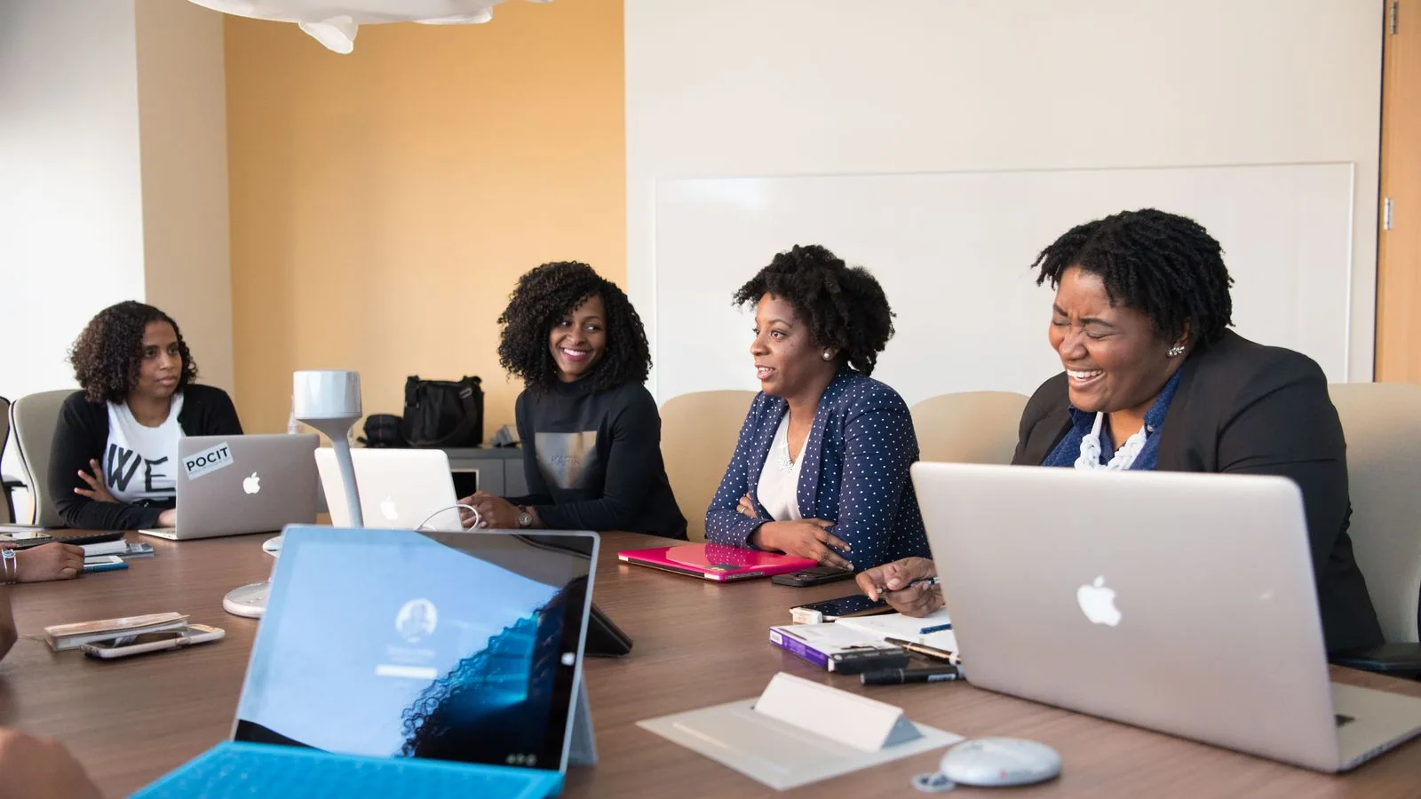 Women discussing information around laptops at a table