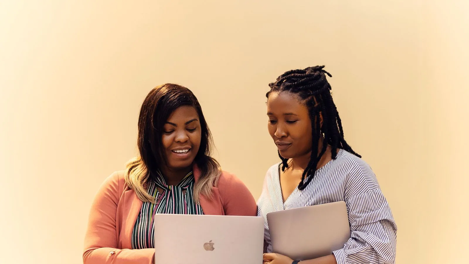 Two colleagues comparing information on a laptop