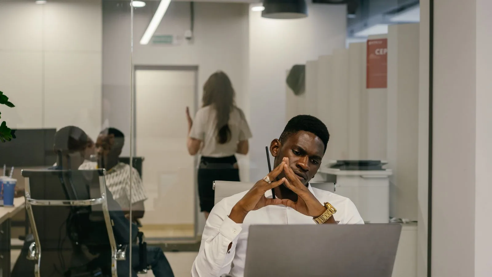 A man thinking while working at a laptop in an office