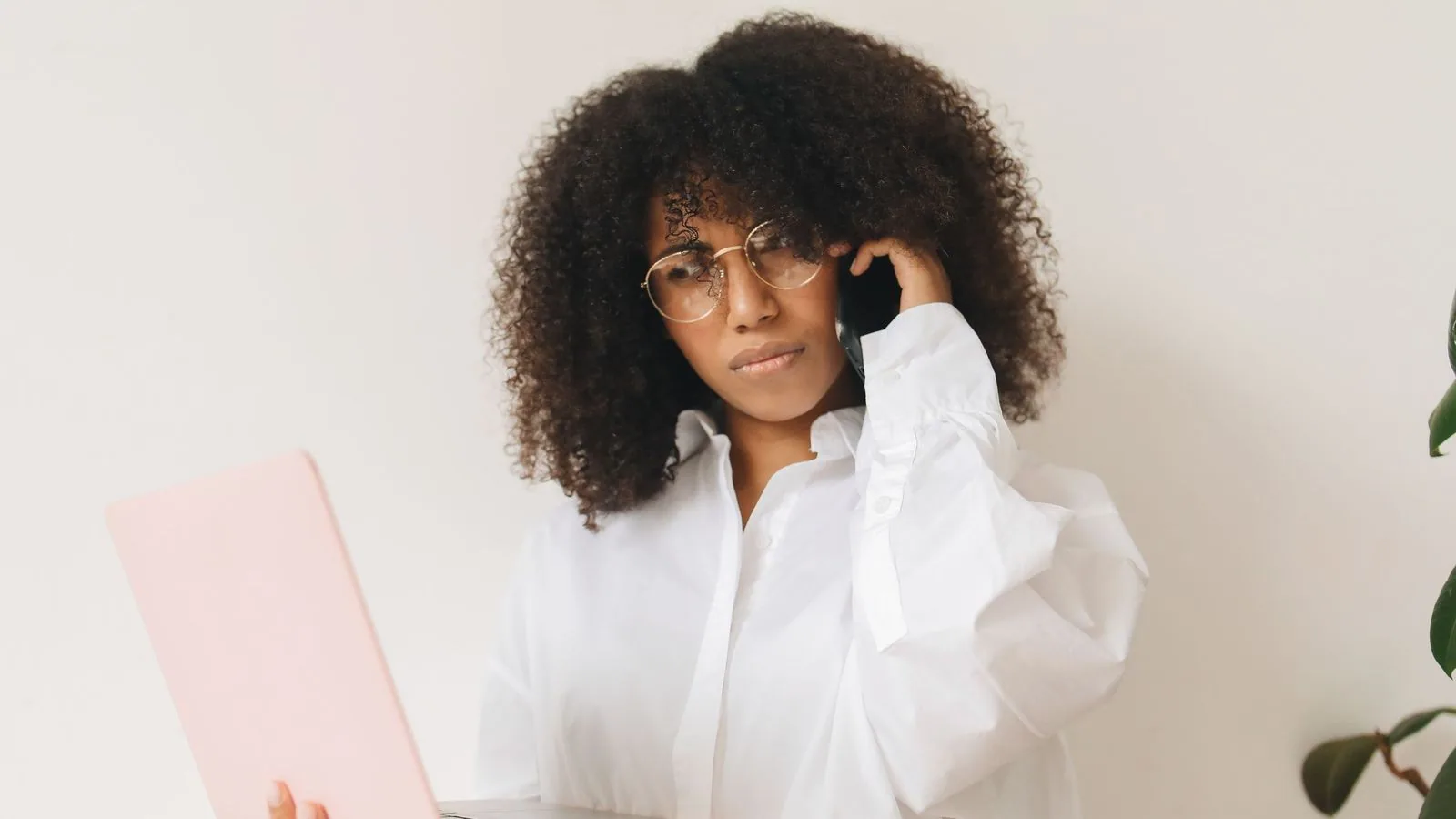 A woman taking a phone call beside an open laptop