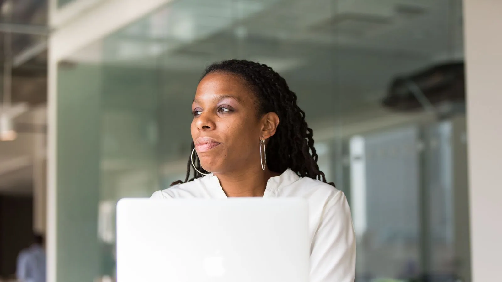 A woman looking over her open laptop in a bright workspace