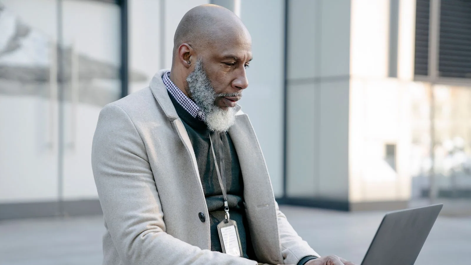 A man typing on a laptop outside an office building