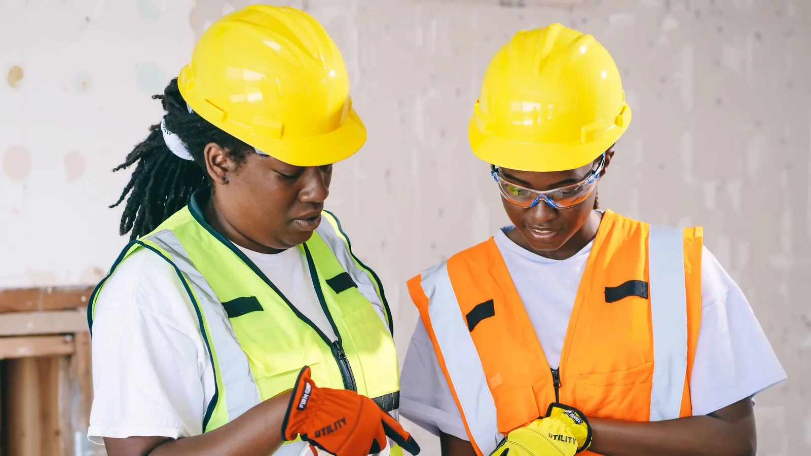 Two engineers in protective equipment checking plans on site