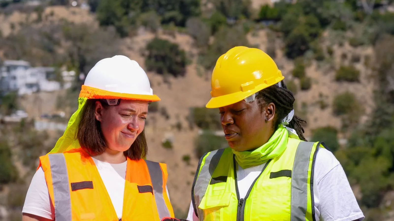 Two engineers reviewing a clipboard at a construction site