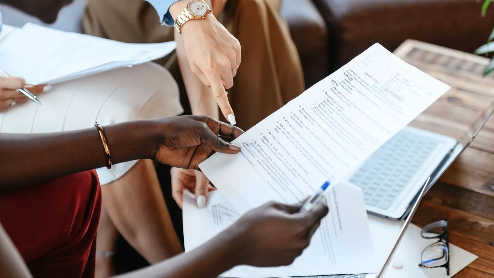 People comparing printed documents beside a laptop