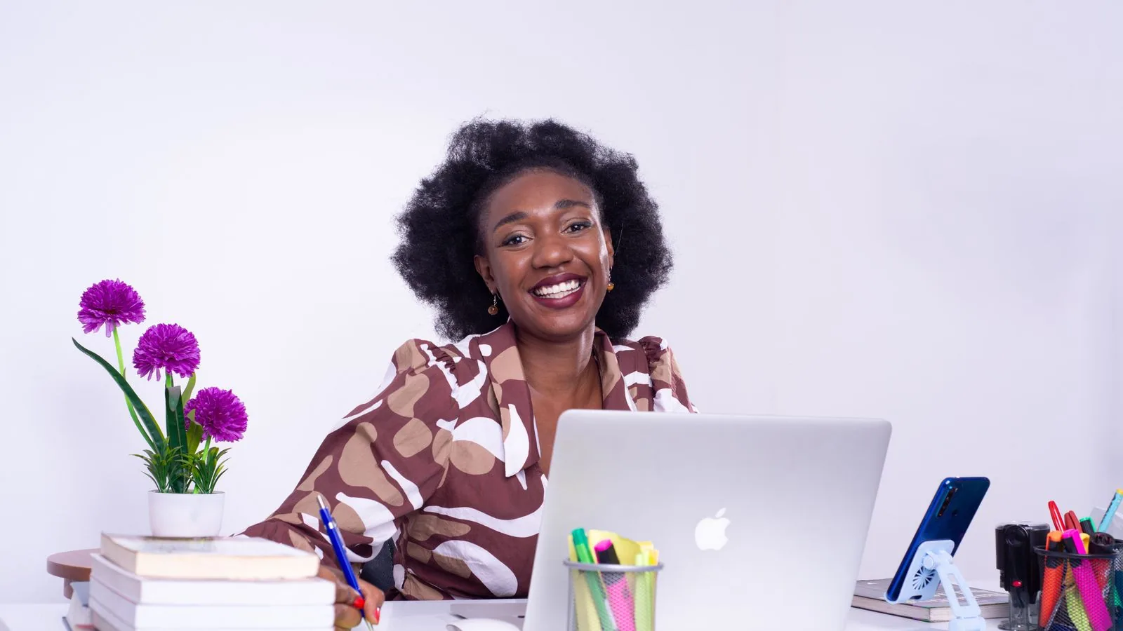 A woman working at a desk with a laptop and notebooks