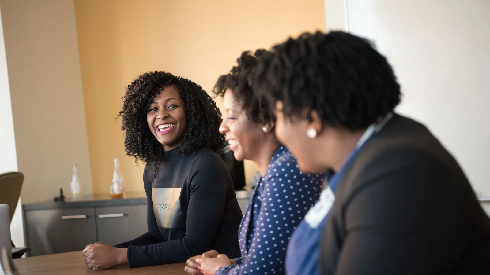 Three women discussing work around an office table