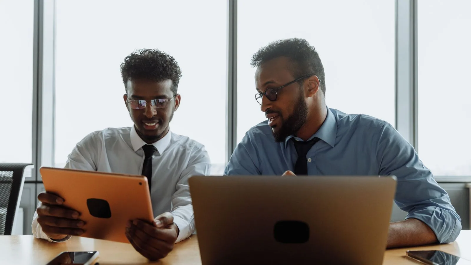 Two colleagues comparing information on digital devices