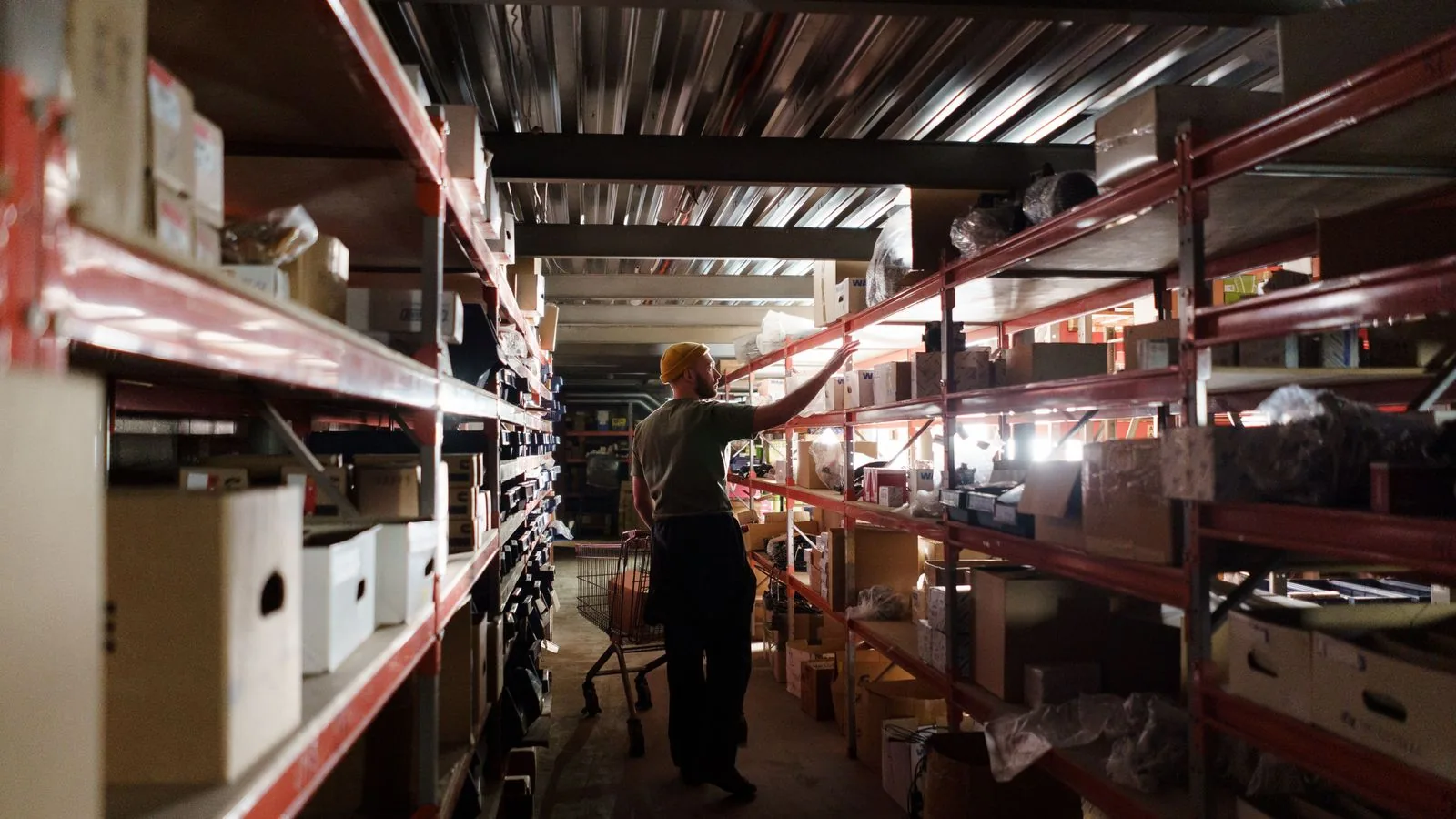 A warehouse worker checking stock along shelving