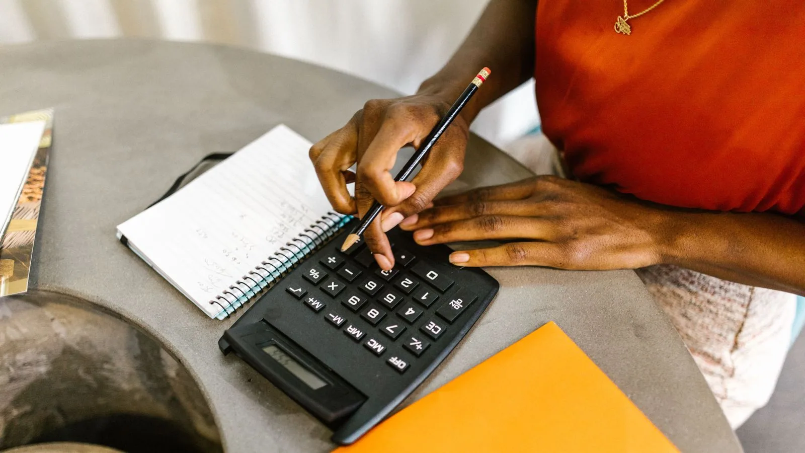 A woman using a calculator beside a notebook